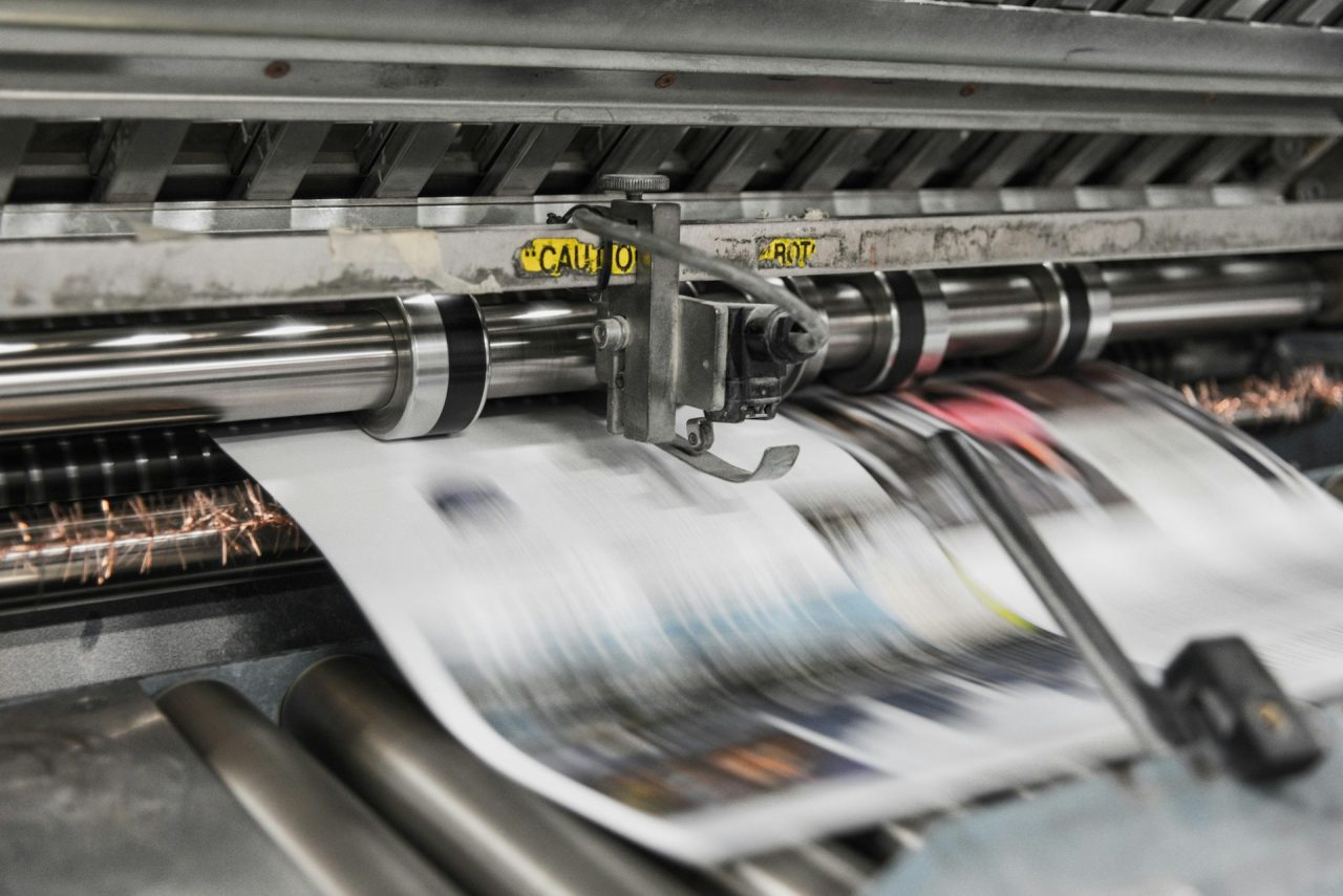 Paper coming out of a mechanical printing press.